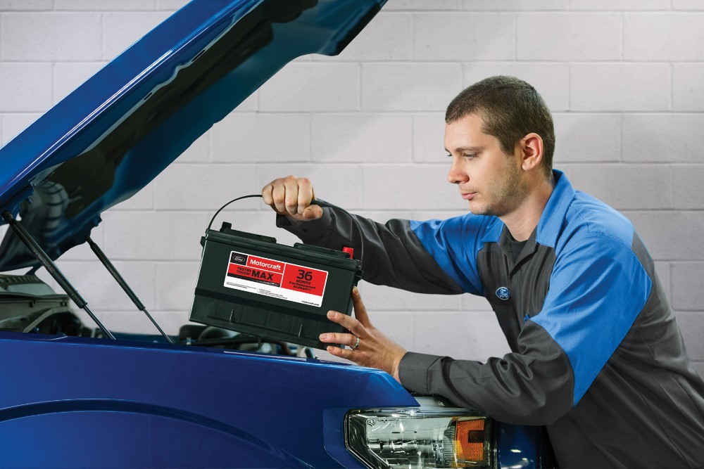 A service worker replaces the battery in the car