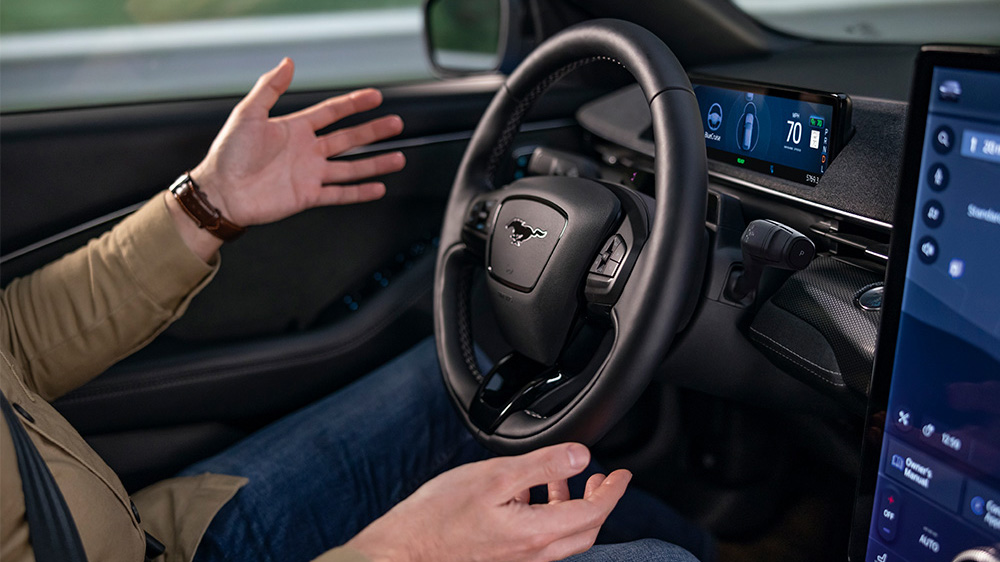 A man sitting in the Ford Mustang Mach-E with his hands away from the steering wheel, showing the BlueCruise technology.