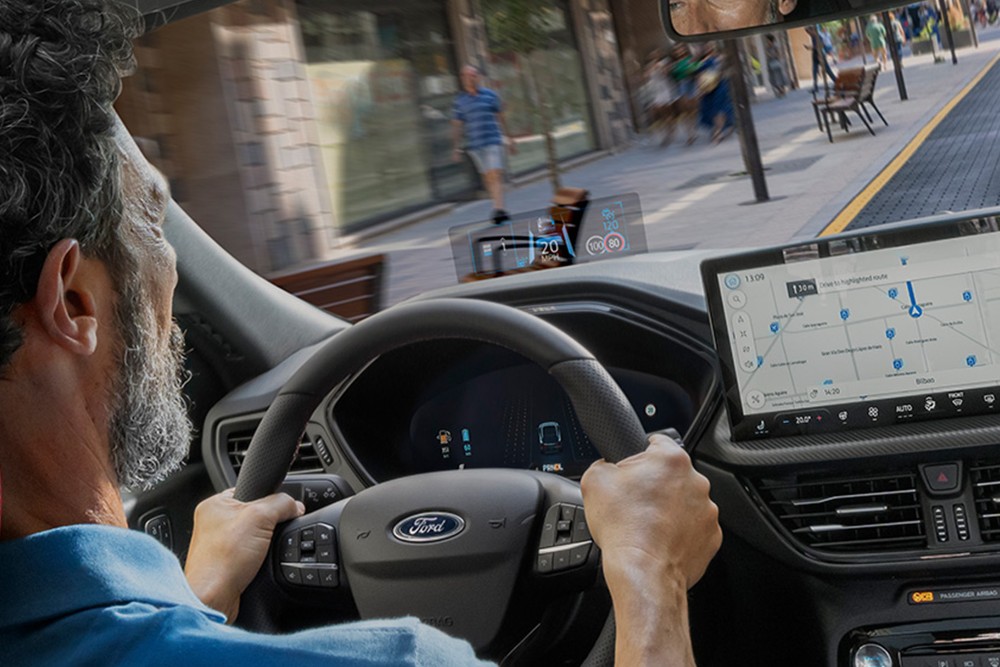 An interior photo of a man driving the Ford Kuga along a city road. 