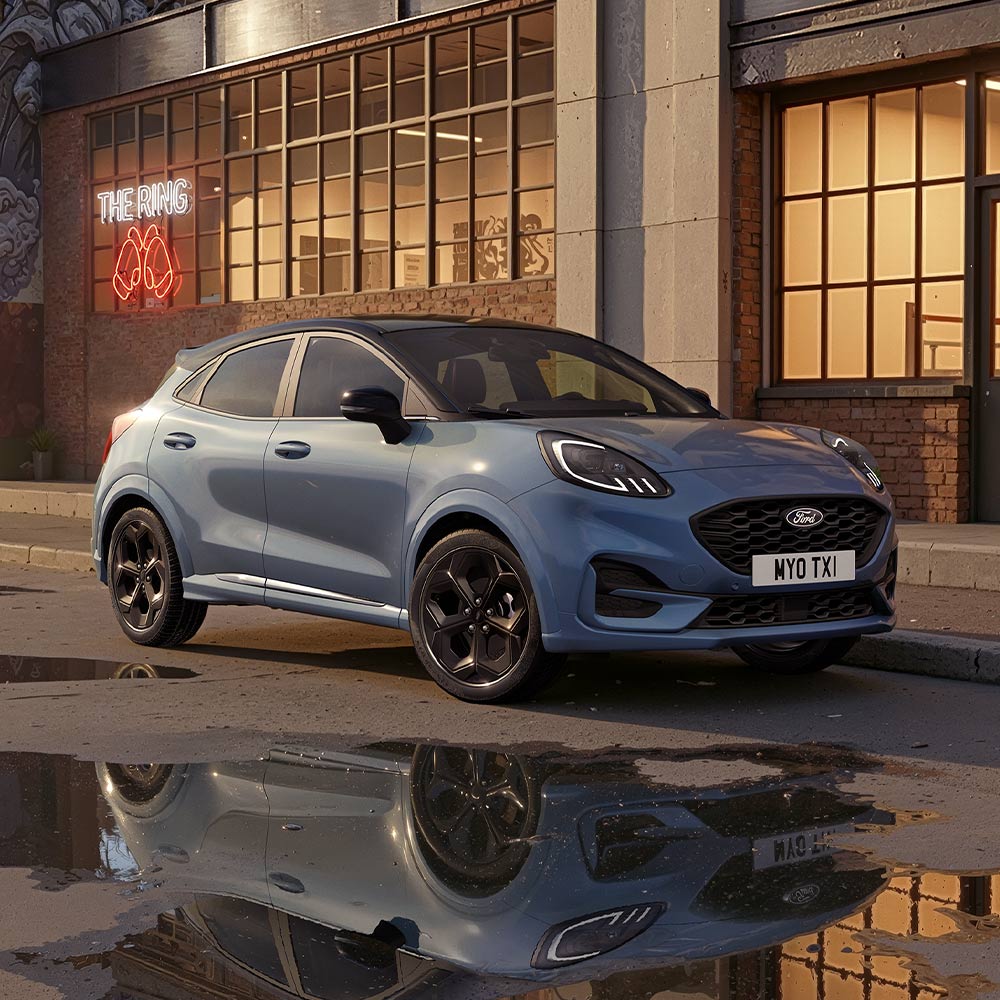 A limited edition Vapour Blue Puma Gen-E parked on a dimly lit city road at night.