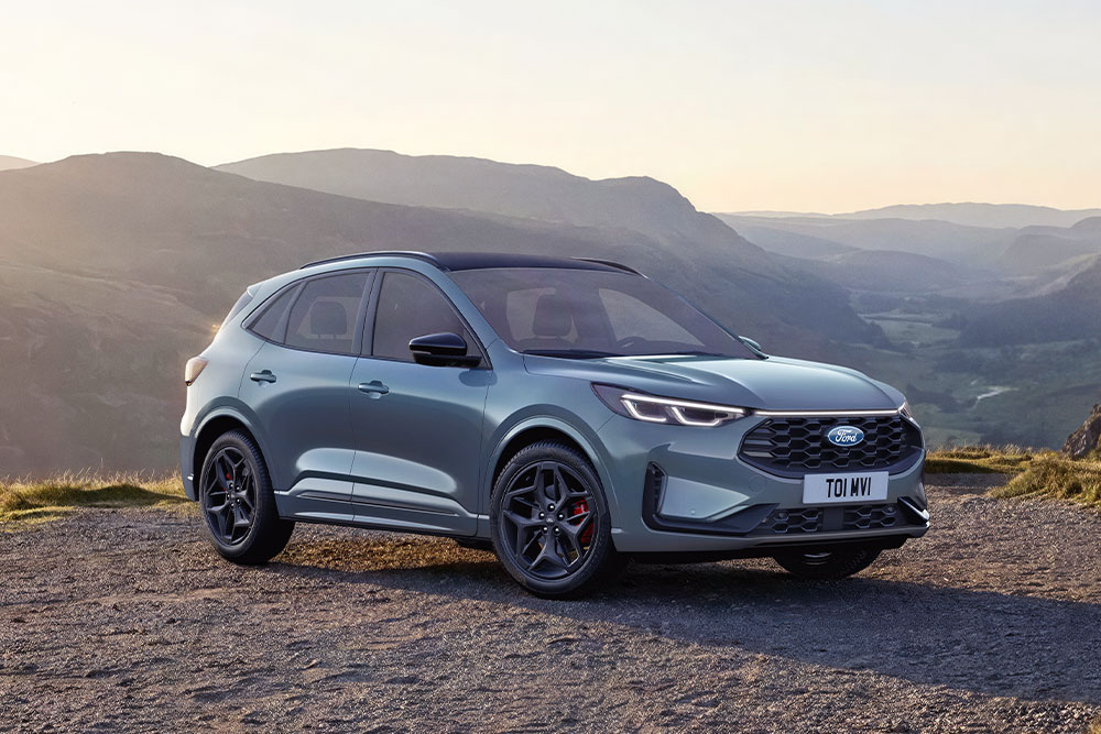 A blue Ford Kuga SUV parked outdoors with a mountainous background.