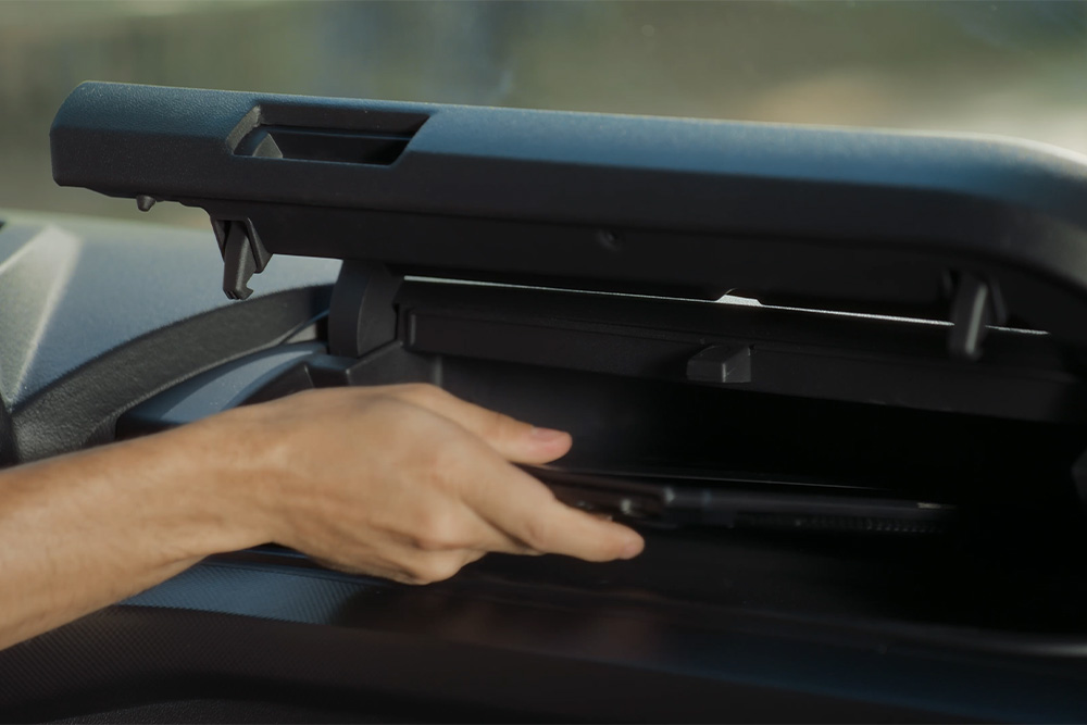 A hand reaches into a compartment above the driver's seat in the Ford Tourneo Custom.