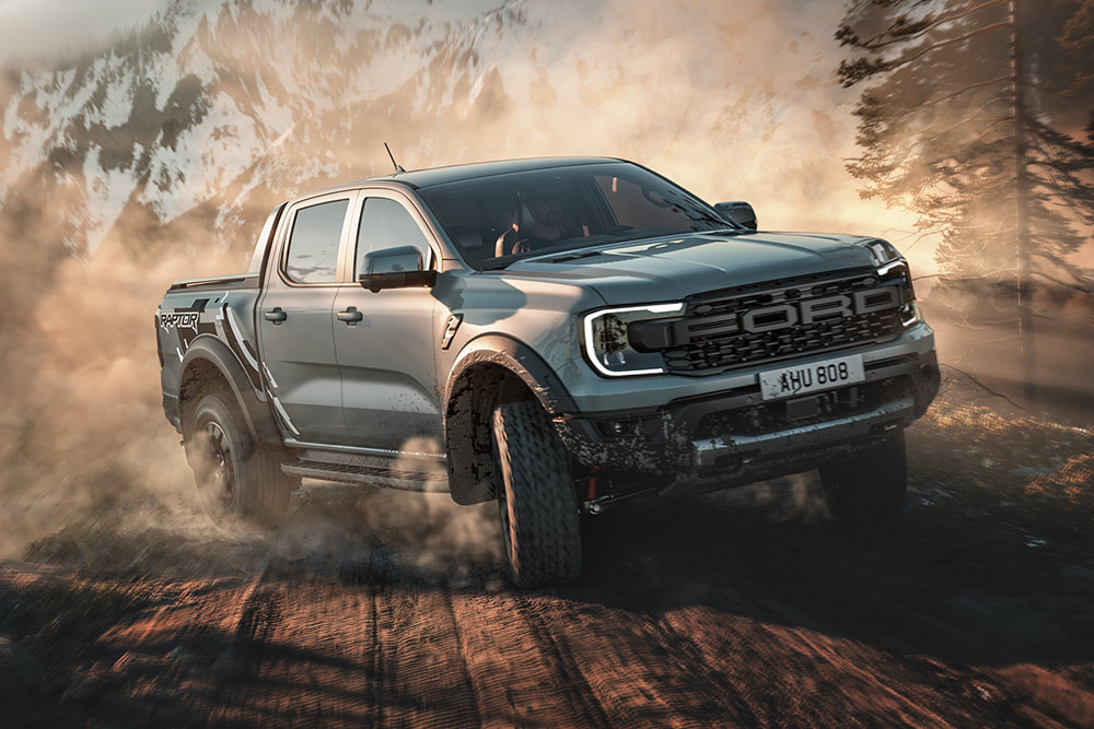 Ford Ranger Raptor in Baja driving on a dirt road, mountainous landscape in the background.