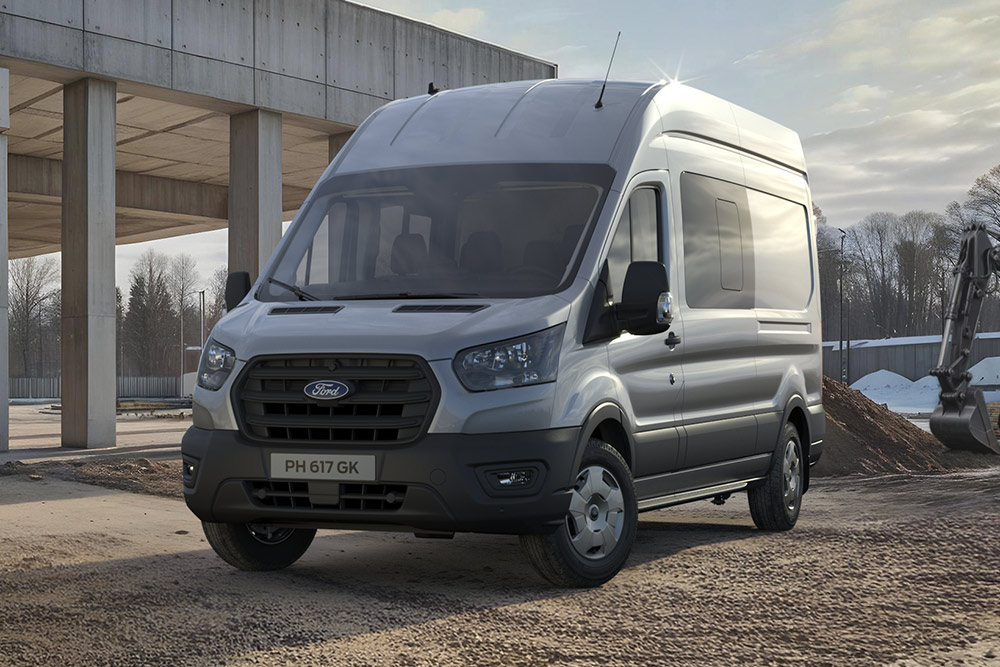 Silver Ford Pro Transit parked on a building site, construction workers in the background.