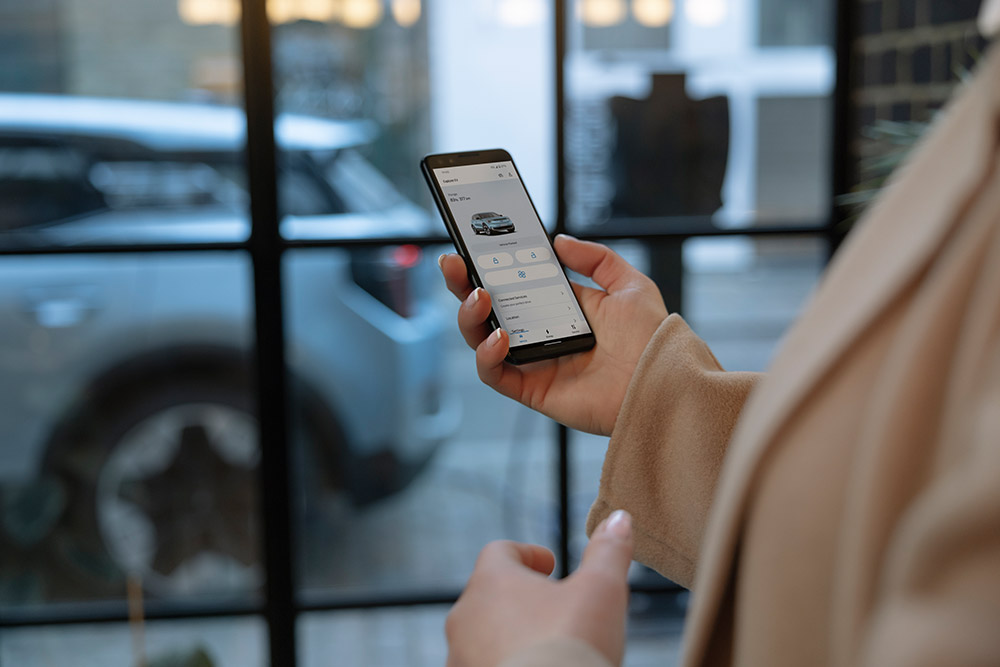 A person holding a smartphone displaying the Ford app with fleet management information.